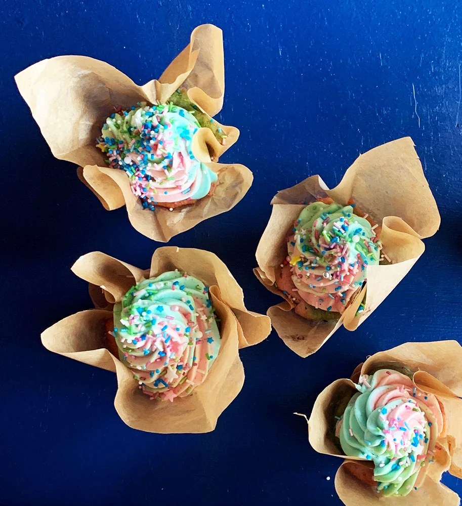 Regnbue Cupcakes med farverig frosting på blå baggrund