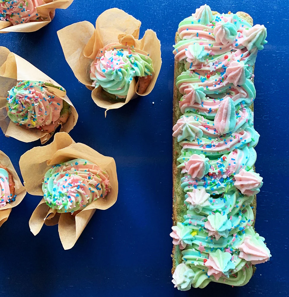 Regnbue Cupcakes og kage med farverig frosting på blå baggrund