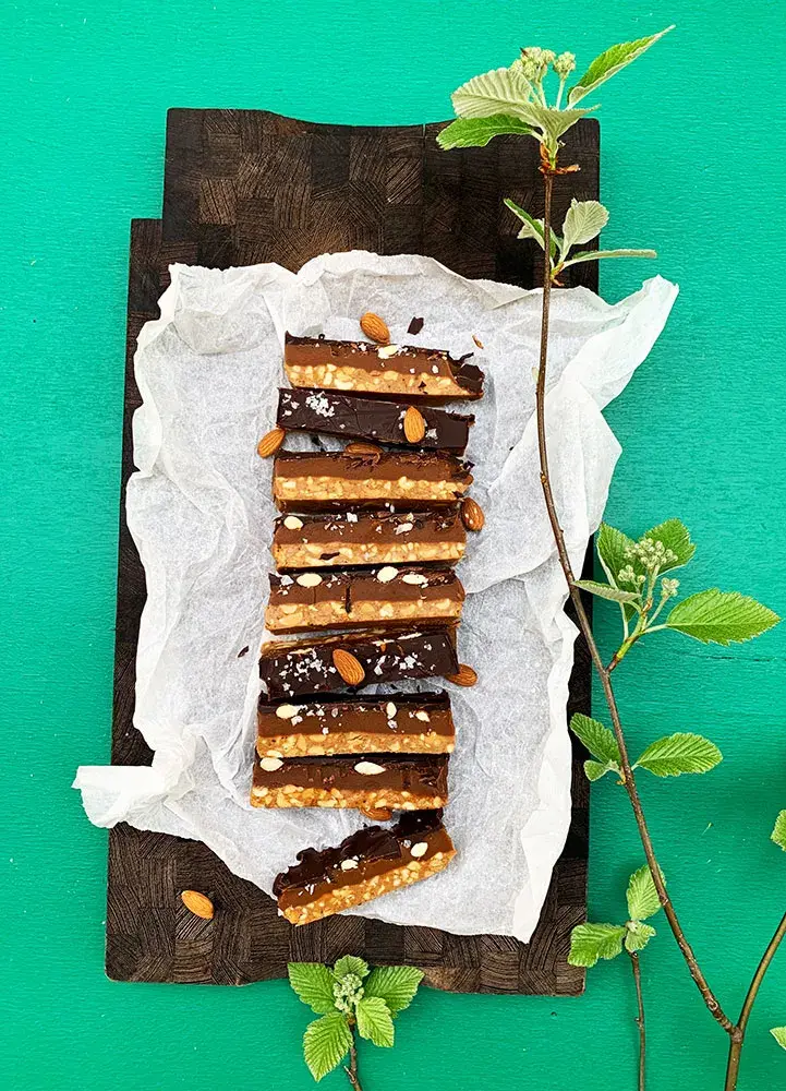 Keto snickers set oppefra på spækbræt med grønne blade