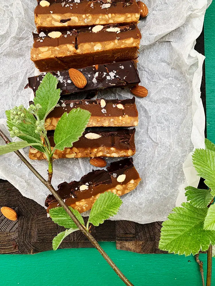 Keto snickers set oppefra på spækbræt med grønne blade